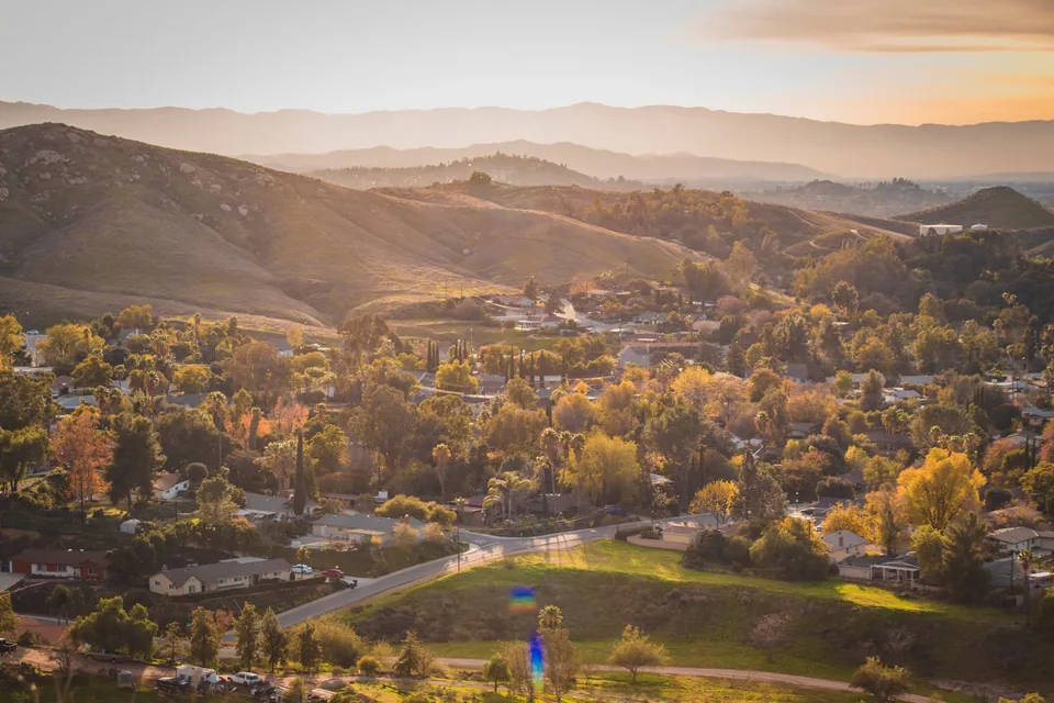 A leafy suburb in a valley at golden hour, layered hills behind